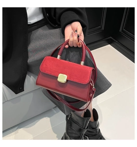 Detail of burgundy leather handbag showing suede contrast flap and gold buckle hardware