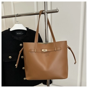 Detail of a brown PU leather bucket bag with gold metal twist lock and drawstring accents