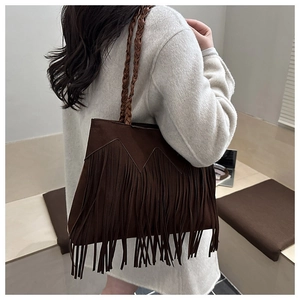 Détail du sac seau en similicuir marron foncé avec de longues franges et sangle tressée