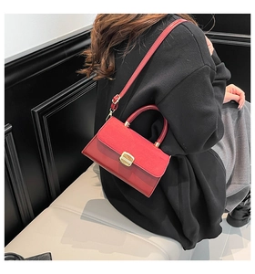 Detail of red leather crossbody bag with suede flap and gold buckle on a model