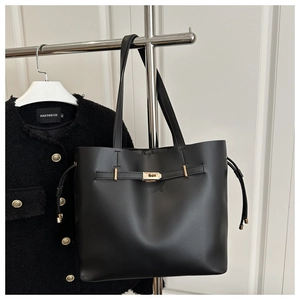 Detail of black leather bucket bag with gold metal twist lock on display