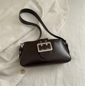 Detail of coffee brown vintage underarm bag with large silver buckle on corduroy background