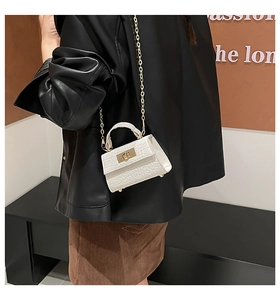 Detail of white crocodile texture handbag with gold twist lock and chain strap