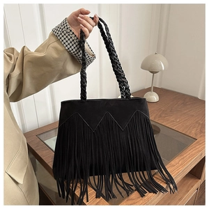 Détail du sac bohème noir à franges avec poignée en cuir tressé artisanal et pompons