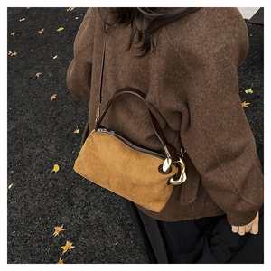 Detail of Boston bag in camel matte leather with gold ring held by model in autumn scenery