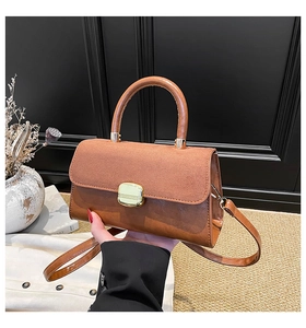 Close-up of brown suede and leather handbag with golden metal buckle and top handle