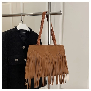 Détail d'un sac cabas bohème en daim marron avec franges et poignée tressée élégante