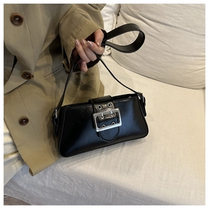 Detail of black faux leather handbag featuring bold silver double-eyelet metal buckles