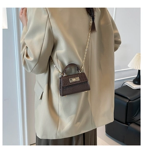 Detail of dark brown faux crocodile leather mini bag with golden metal twist lock and chain