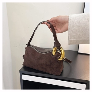Detail of dark brown suede Boston bag with oversized gold chain and smooth leather handles