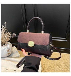 Detail of dual-texture handbag with brown suede flap and golden metallic clasp