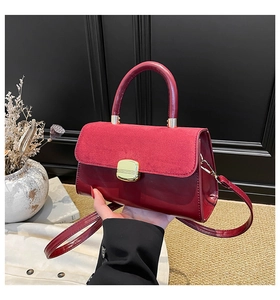 Detail of burgundy textured leather handbag featuring a sleek gold rectangular clasp
