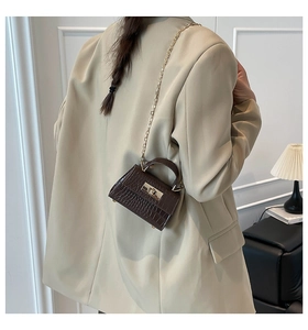 Detail of dark brown faux crocodile leather mini handbag with gold chain strap