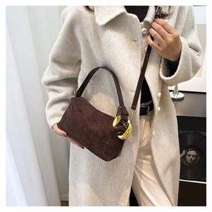 Detail of dark brown suede Boston bag with gold metal ring and detachable shoulder strap
