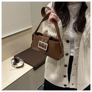 Detail of vintage dark brown shoulder bag with large silver buckle on knit cardigan