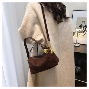 Detail view of dark brown suede Boston bag with golden metal rings and adjustable strap