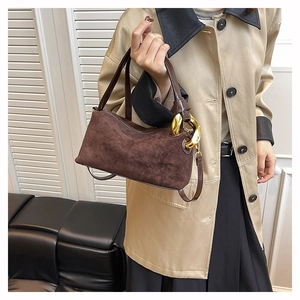 Detail of dark brown matte leather Boston bag with chunky gold hardware held by a model