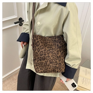 Close-up of leopard print tote bag with brown leather strap on a trench coat