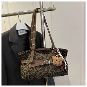 Detail der Leoparden-Wildleder-Einkaufstasche mit braunem Lederriemen und Bärenanhänger