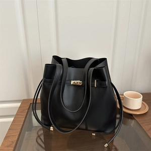 Chic black matte leather bucket bag with gold hardware shown on a minimalist table