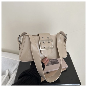 Detail of beige baguette bag with a prominent square silver metal buckle and wide strap