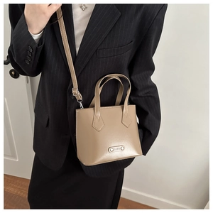 Detail of light brown bucket bag featuring silver hardware and FASHION metal plate