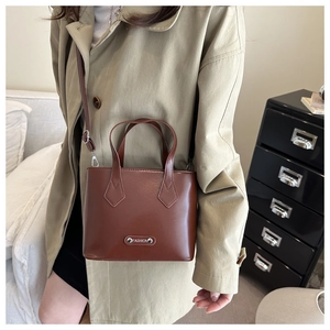 Detail of brown PU leather crossbody bucket bag with silver Fashion metal plate