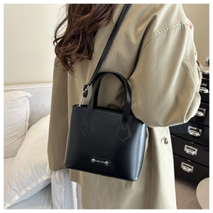 Close-up of black matte leather mini bucket bag featuring a silver metal logo plate