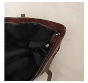 Close-up of the smooth metal zipper and black fabric lining on dark brown leather tote bag