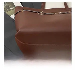 Close-up of precise stitching on a brown leather tote bag with elegant gold hardware
