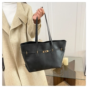 Detail of black leather tote bag featuring a golden metal twist lock and fine texture