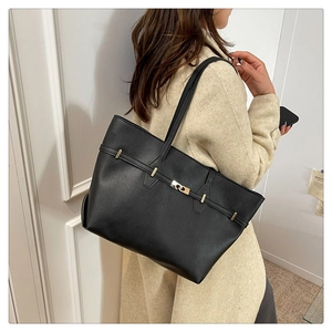 Close-up of black matte leather tote bag featuring elegant golden twist-lock buckle detail