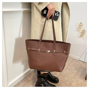 Detail of caramel brown leather tote bag with stylish metal twist lock and matte finish