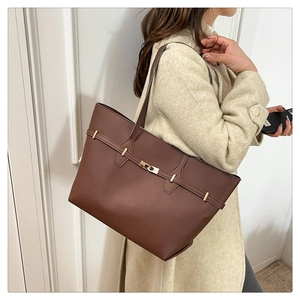 Brown leather tote bag featuring a gold buckle shown styled with a wool coat