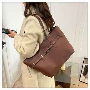 Detail of a large dark brown faux leather tote bag with stylish metal buckle and strap