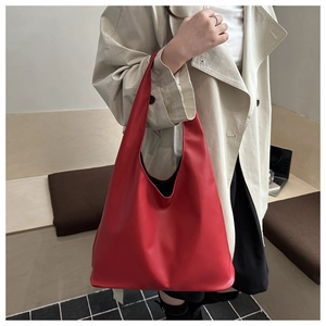 Détail d'un sac cabas en cuir rouge avec poignée minimaliste et trench-coat élégant