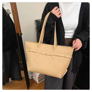 Detail of a large beige PU leather tote bag with elegant gold buckle for office use