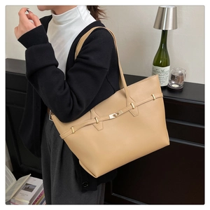 Detail of beige large capacity tote bag with decorative strap and metallic buckle