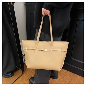 Detail of light beige tote bag with gold buckle and slim straps for office wear