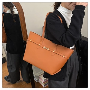Brown leather tote bag detail with slim strap and metallic buckle on female model
