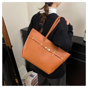 Detail of a large orange PU leather tote bag worn by a model in a modern home setting