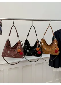 Detailed view of three rivet tote bags in suede with colorful pompoms and tassels