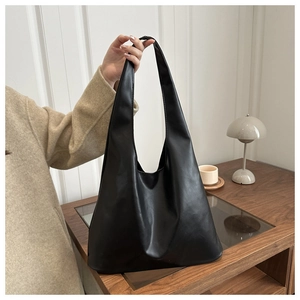 Détail du grand cabas en cuir noir mat présenté dans un décor d'intérieur minimaliste