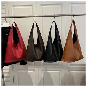 Série de grands sacs fourre-tout en rouge, marron, noir et caramel sur un support