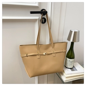 Detail view of khaki leather tote bag hanging on door with artistic background decor