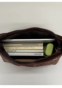 Spacious interior of dark brown tote bag holding tablet, books, and umbrella