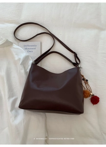 Detail of dark chocolate matte leather tote with colorful ethnic charm and wide strap