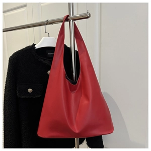Détail d'un grand sac cabas rouge en cuir mat porté avec une veste en tweed noire