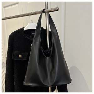 Vue détaillée d'un grand sac cabas en cuir mat noir suspendu à côté d'une veste