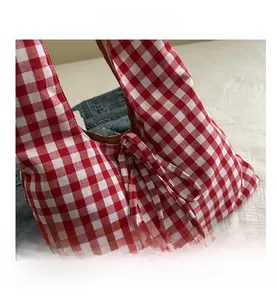 Close-up of red and white gingham tote bag with tie detail on woven cotton fabric